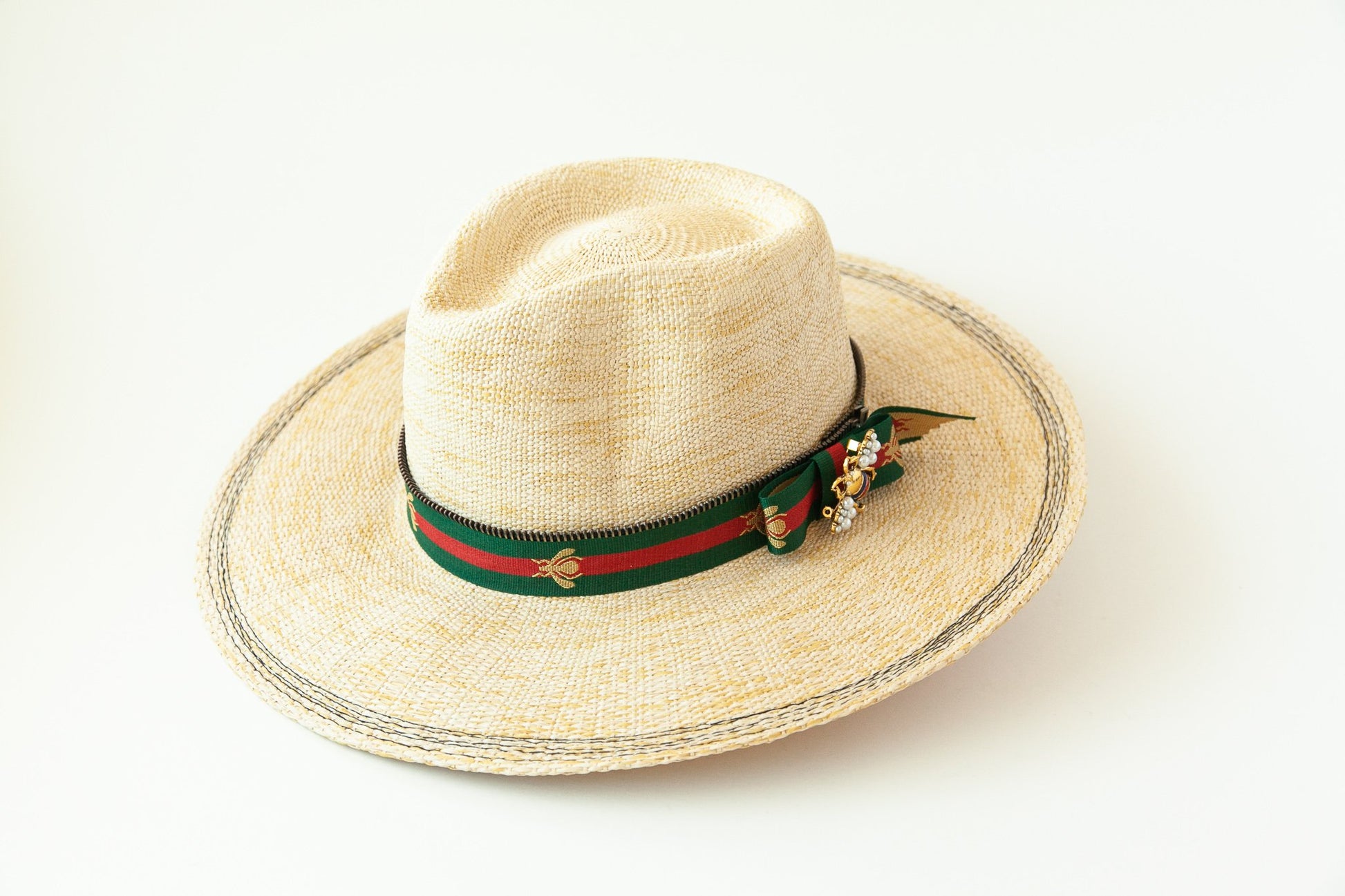 Woven hat with decorative band and bee charm