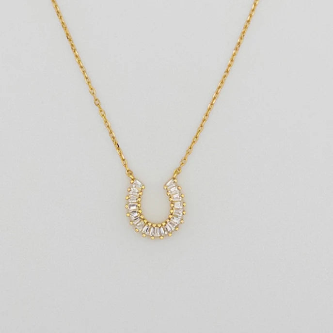 Close up of gold plated necklace with horseshoe charm