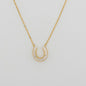 Close up of gold plated necklace with horseshoe charm