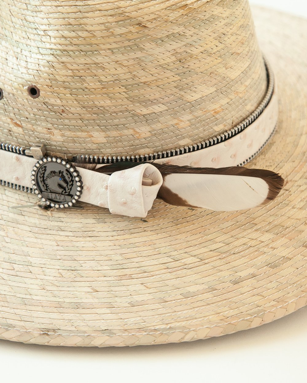 Close-up of white leather band, feather and logo medallion